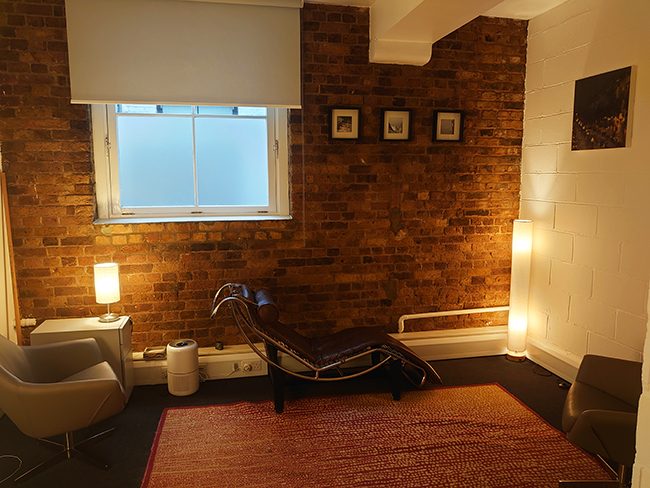 Consulting room with analytic couch, armchair, and exposed brick wall, Coppergate House